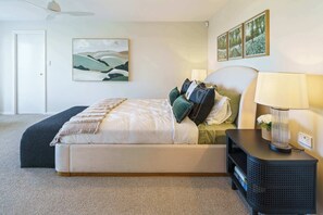 A bedroom with a bed, bedside table, lamp, and artwork on the wall.
