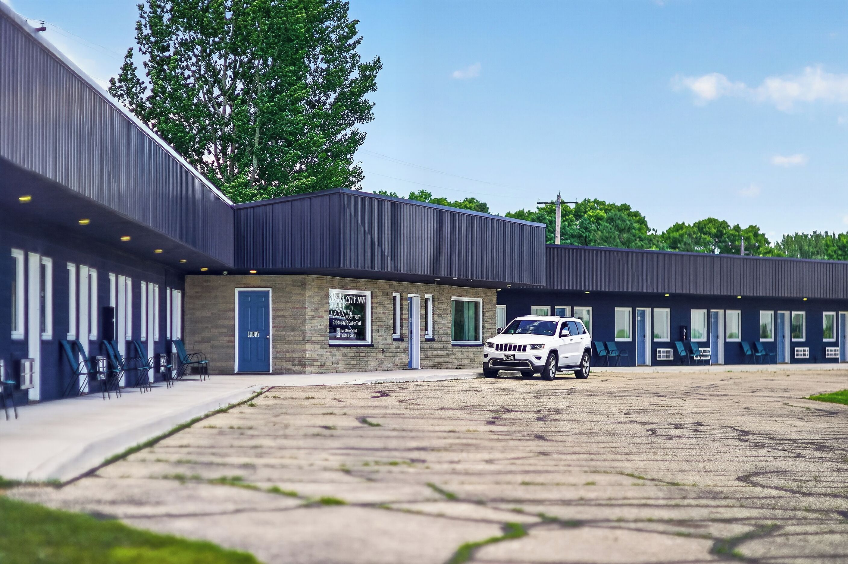 A building with a covered parking area, a lobby entrance, and multiple windows.