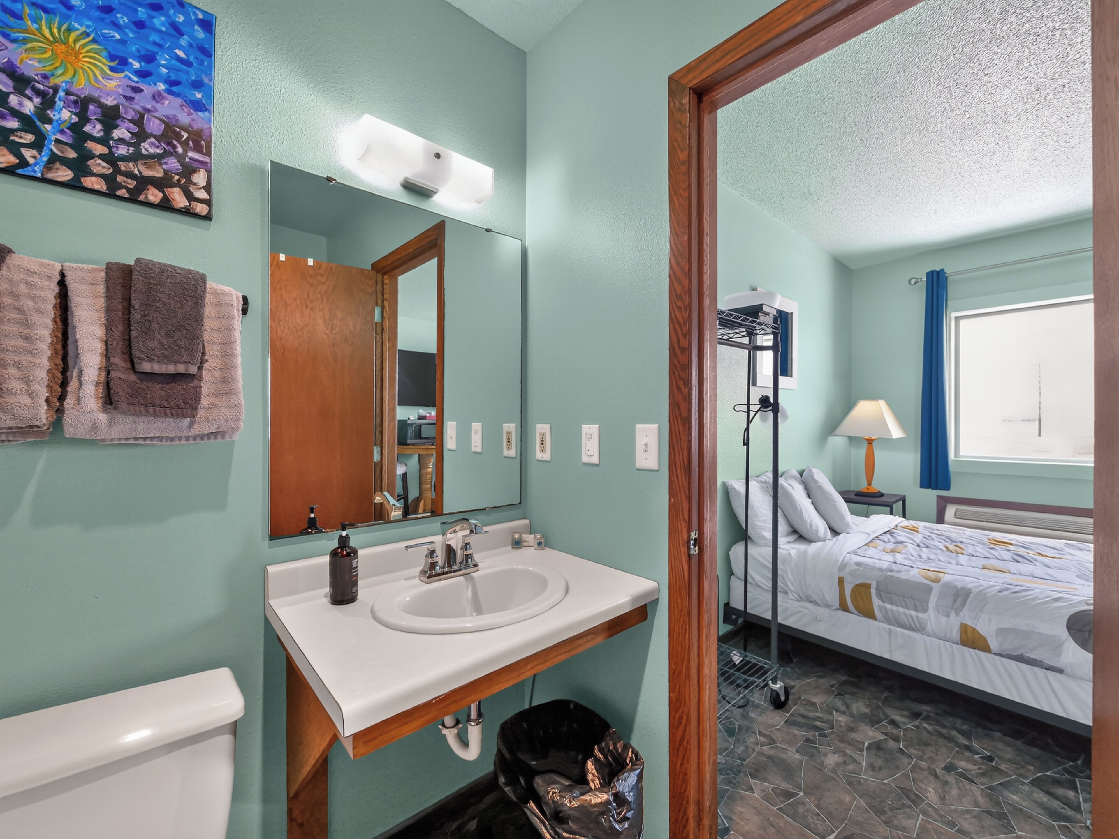 A bathroom with a sink, mirror, towels, and a toilet.