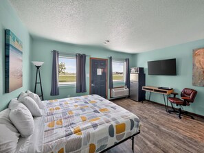 Ett hotellrum med en säng, ett skrivbord, en stol, en tv och ett fönster med gardiner.