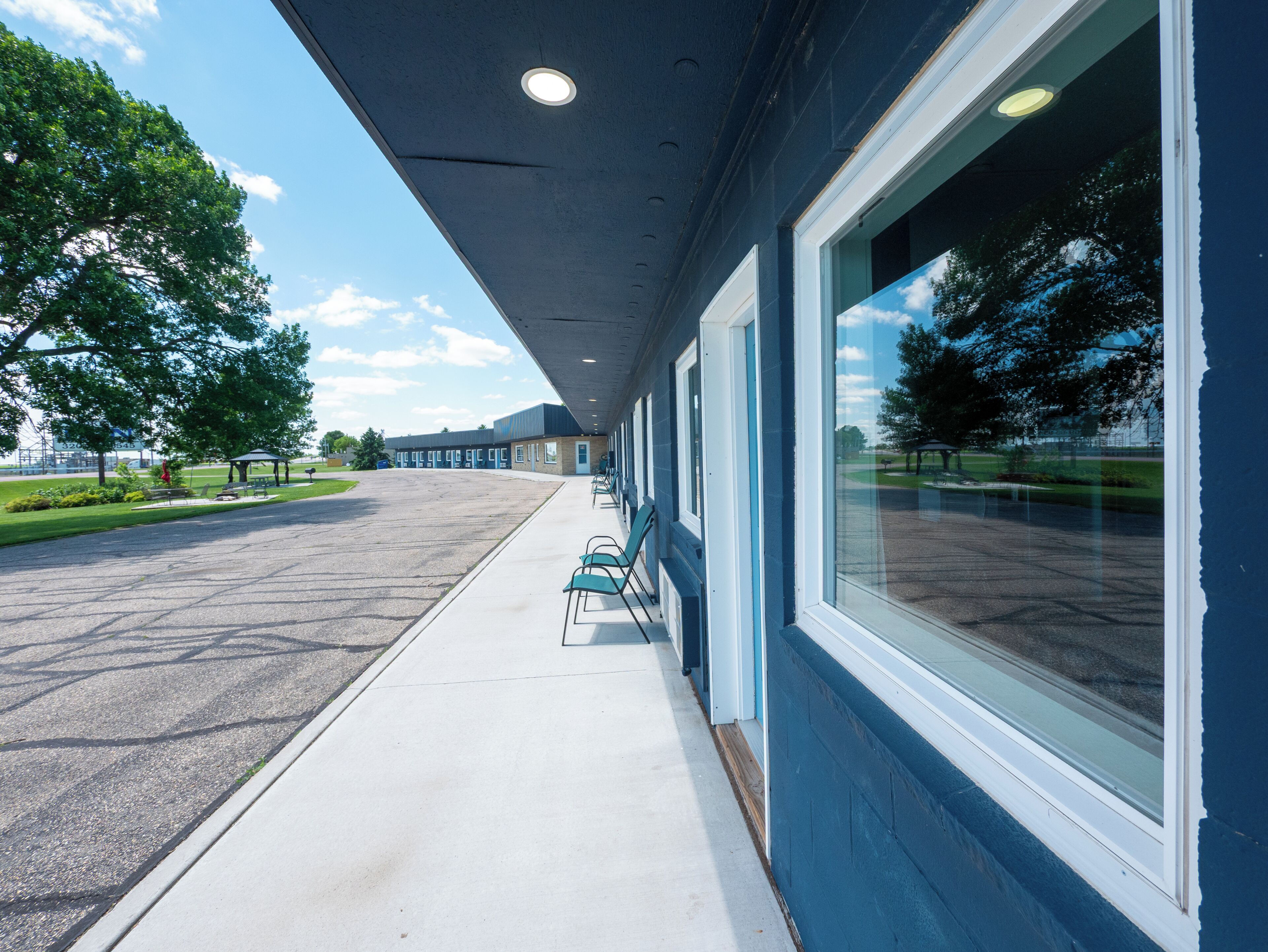 A building with a covered walkway, large windows, and a parking lot.
