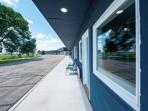 A building with a covered walkway, large windows, and a parking lot.