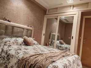 Un dormitorio con cama, espejo y armario.