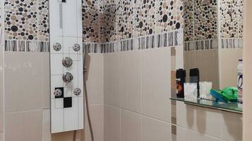 A bathroom with a shower, a sink, and toiletries.
