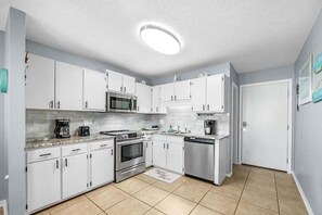 A compact kitchen with white cabinets, a microwave, stove, and dishwasher. - Perfect Gulf Shores Getaway With Pools, Hot Tubs and Beach Access (Gulf Shores)