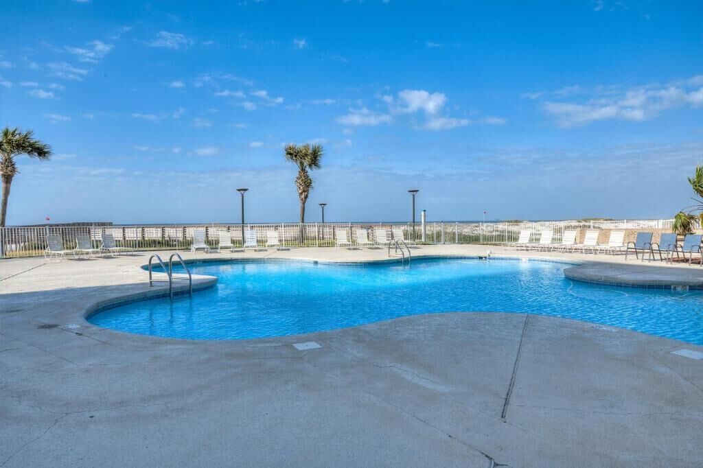 Una piscina de diseño curvo, rodeada por una terraza de concreto y barandales de metal.