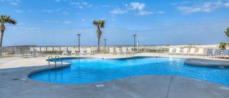 Una piscina de diseño curvo, rodeada por una terraza de concreto y barandales de metal.