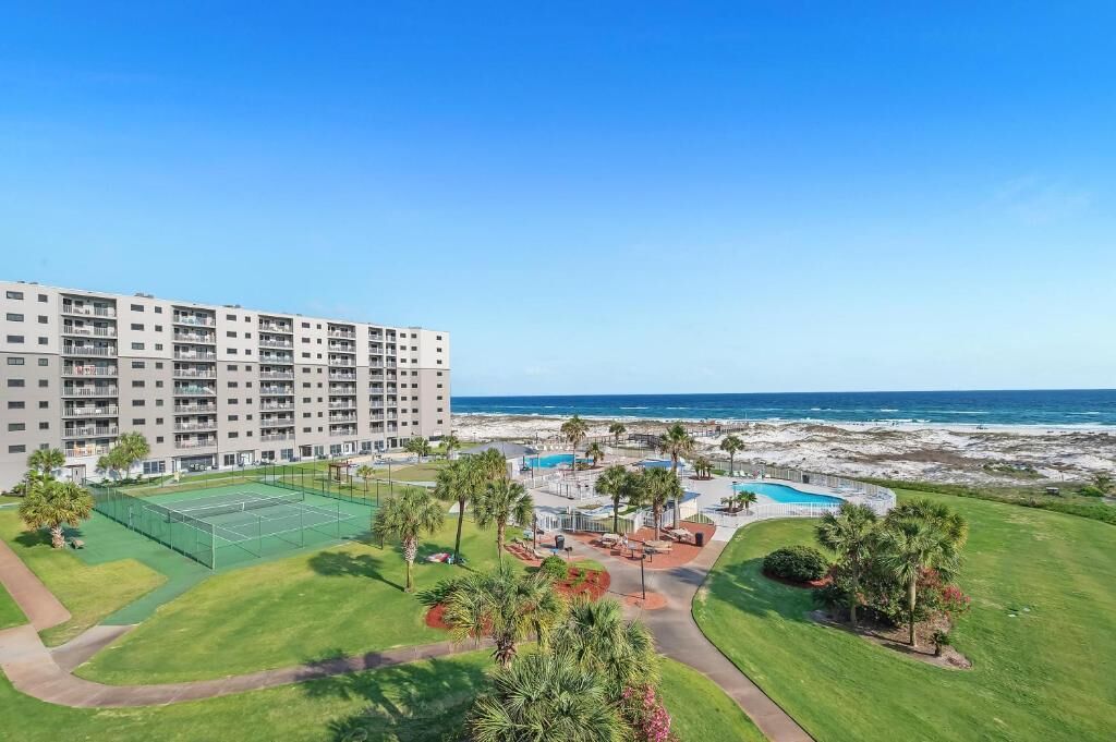 A hotel with a tennis court, pool, and ocean view.
