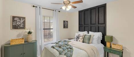 A bedroom with a bed, a ceiling fan, a window with blinds, and a green dresser.