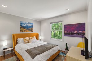 A modern bedroom with a large bed, a window with a view of trees, and two wall-mounted paintings. - Modern Mountain Retreat - 4-bedroom, family friendly, peaceful (Durango)