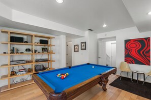Ein Zimmer mit Billardtisch, einer Holzregaleinheit und einem Bild an der Wand.