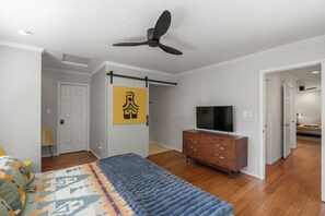 A bedroom with a bed, a TV, a ceiling fan, a dresser, and a door leading to another room. - Modern Mountain Retreat - 4-bedroom, family friendly, peaceful (Durango)