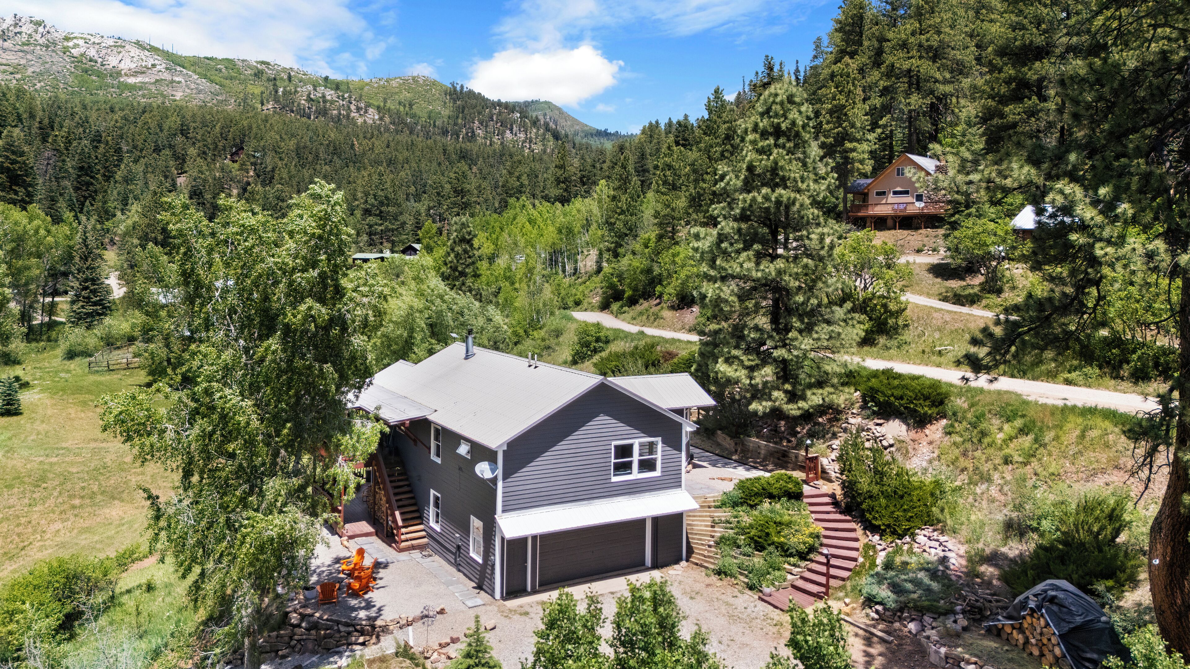Ein zweistöckiges Haus mit Garage, eingebettet in eine bewaldete Landschaft mit einem Berg im Hintergrund.