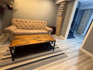 A living room with a tufted sofa, a wooden coffee table, and a striped rug.