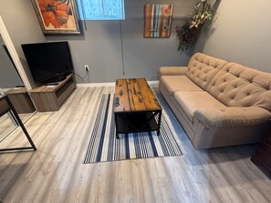 A living room with a television, a sofa, a coffee table, and a striped rug.