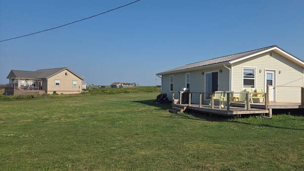 A single-story house with a porch, a deck, and outdoor seating.