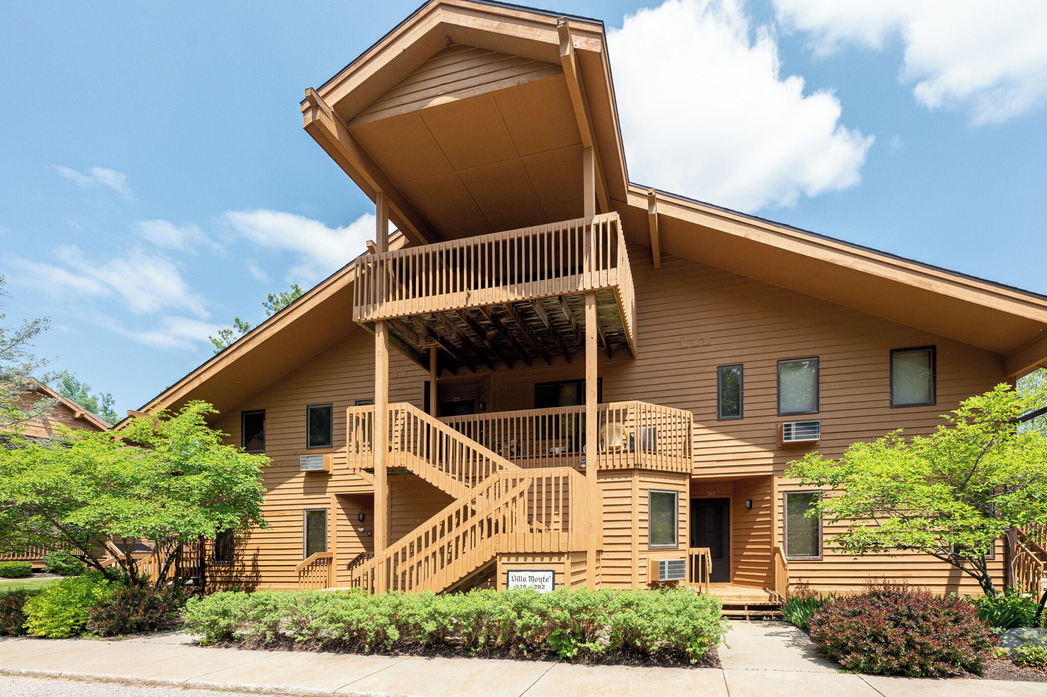 A two-story building with a wooden exterior, a balcony on the upper floor, and a staircase leading to the entrance.