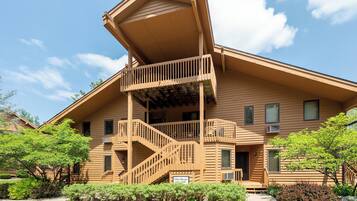 A two-story building with a wooden exterior, a balcony on the upper floor, and a staircase leading to the entrance.