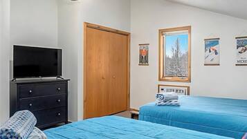 A bedroom with two beds, a ceiling fan, a TV, and a wardrobe.