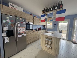 Een moderne keuken met een ingebouwde oven, een koelkast en een wijnrek.