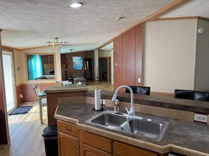 A kitchen with a sink, countertop, and wooden cabinets.