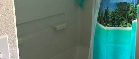 Un baño con cortina de ducha que muestra una escena tropical.