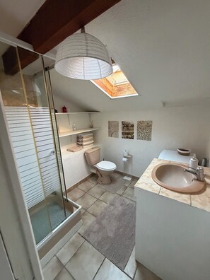 Ein Badezimmer mit Toilette, Waschbecken und Duschbereich.