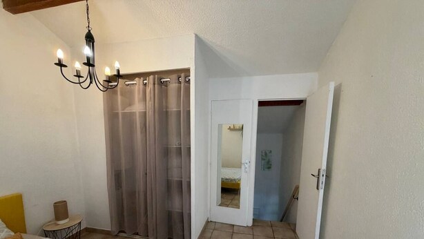 Ein Schlafzimmer mit Bett, Nachttisch, einer Chandelierleuchte, einem Schrank mit Schiebetür und einer Tür zu einem Badezimmer.