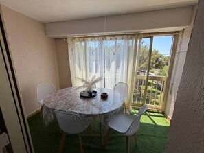 A round table with four chairs, a decorative centerpiece, and a view of a garden through a glass door. - Charming south-facing 2-bedroom duplex – sleeps up to 4 adults – 300 m from the ocean (Six-Fours-les-Plages)