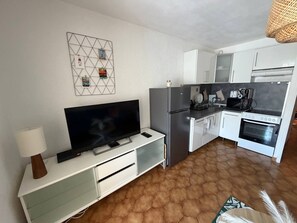 A modern kitchen with a flat-screen TV, white cabinets, a refrigerator, and a stove. - Charming south-facing 2-bedroom duplex – sleeps up to 4 adults – 300 m from the ocean (Six-Fours-les-Plages)