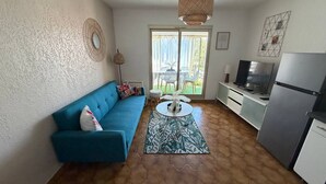 Ein gemütlicher Wohnbereich mit Sofa, Couchtisch, Fernseher und Kühlschrank.