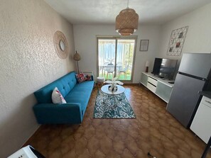 A compact living space with a sofa, a coffee table, a television, and a refrigerator. - Charming south-facing 2-bedroom duplex – sleeps up to 4 adults – 300 m from the ocean (Six-Fours-les-Plages)