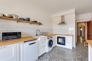 A compact kitchen with a microwave, sink, washing machine, and wooden countertop. - Sea Views • Huge Terrace • Steps to Old Town (Lagos)