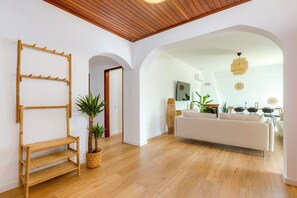 A modern living space with a wooden floor, a white sofa, a bamboo shelf, and a large plant. - Sea Views • Huge Terrace • Steps to Old Town (Lagos)