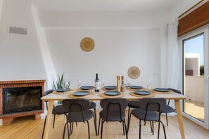 A dining area with a table set for six, a fireplace, and a view through a large window. - Sea Views • Huge Terrace • Steps to Old Town (Lagos)