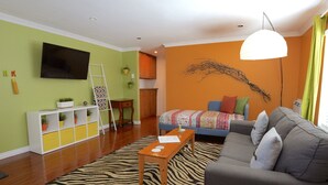 Un salon moderne avec un tapis à motifs zébrés, un canapé gris, une table basse en bois et un téléviseur fixé au mur.