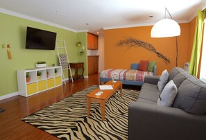 Ein modernes Wohnzimmer mit einem zebra-muster Teppich, einem grauen Sofa, einem Holztisch und einem an der Wand montierten Fernseher.