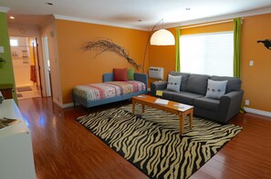 Ein Wohnzimmer mit einer Couch, einem Couchtisch, einem Teppich mit Zeprazmuster und einer wandmontierten Klimaanlage.