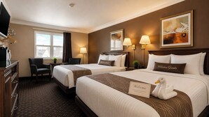 Een hotelkamer met twee bedden, een bureau, een stoel, een televisie en een raam.