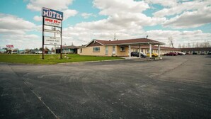 Een motel met een naambord, een overdekte parkeerplaats en een gebouw met een plat dak.