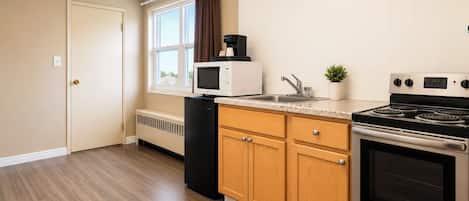 A kitchen with a stove, microwave, sink, and cabinets.