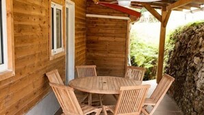 A wooden cabin with a tiled patio, a round table, and four chairs. - Jasmin: Spacious, quiet apartment with a pool for 6 (Le Gosier)