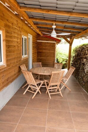 A wooden cabin with a tiled patio, a round table, and four chairs. - Jasmin: Spacious, quiet apartment with a pool for 6 (Le Gosier)