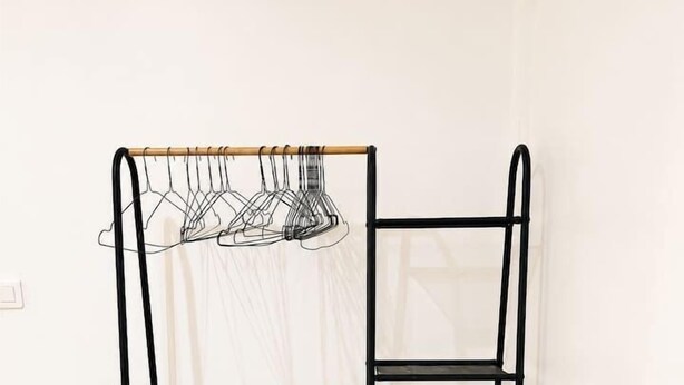 A black metal shelf unit with a ladder and a hanging rack against a white wall. - Jasmin: Spacious, quiet apartment with a pool for 6 (Le Gosier)