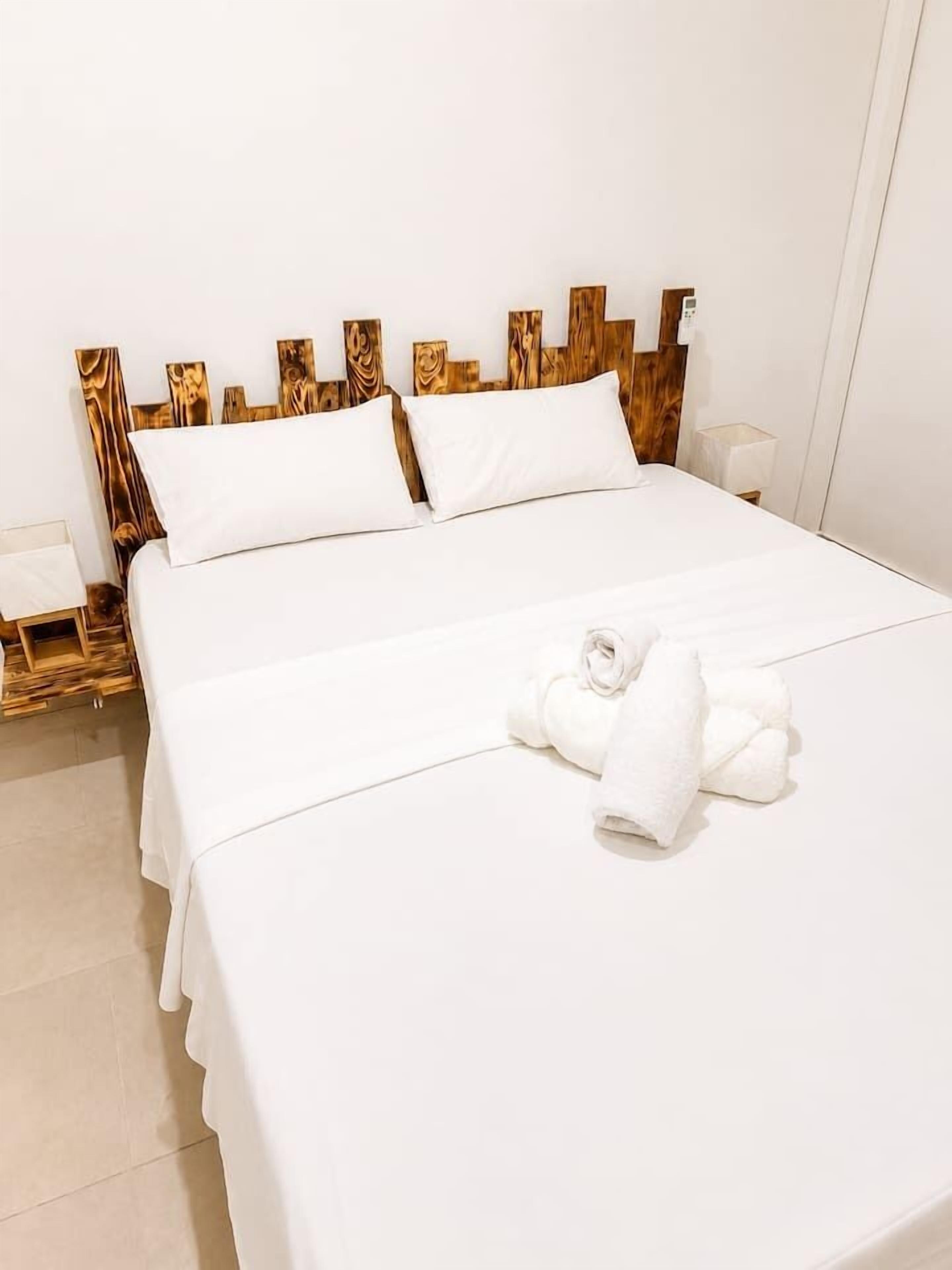 Ein Hotelzimmer mit einem Bett, weißen Leinen und einem hölzernen Kopfteil.