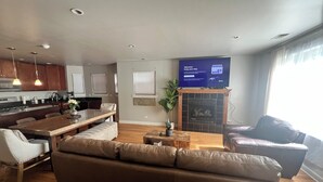 Ein modernes Wohnzimmer mit einer Couch, einem Essbereich mit Tisch und einer Küche im Hintergrund.