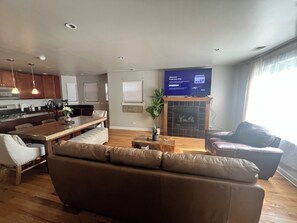 A modern living room with a sofa, a dining area with a table, and a kitchen in the background. - 2-bedroom apartment in awesome Chicago with cool AC (Chicago)