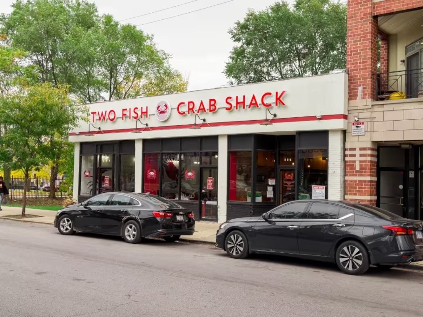 Ein zweistöckiges Gebäude mit einer Schaufensterfront, auf der 'Two Fish Crab Shack' steht.