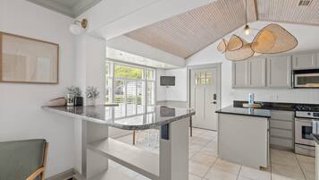 Een moderne keuken met een groot schiereiland, inbouwapparatuur en een eethoek met uitzicht.