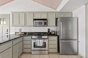 A kitchen with a stove, oven, microwave, and refrigerator.